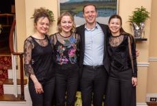 Counterpoint Concert musicians in their concert dress posing in front of a painting and staircase.